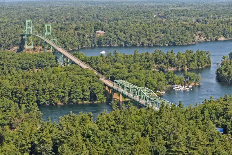 The green Thousand Islands Bridge crossing wooded islands on the St. Lawrence River in summer
