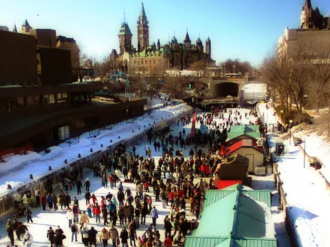 Crowds skating the Rideau Canal Skateway during Winterlude, with the Parliament towers behind